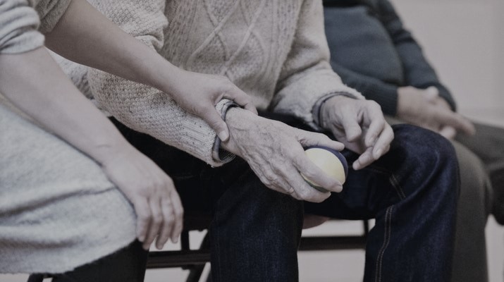 oudere man met balletje in de hand wordt bij de pols vastgehouden door jongere vrouw