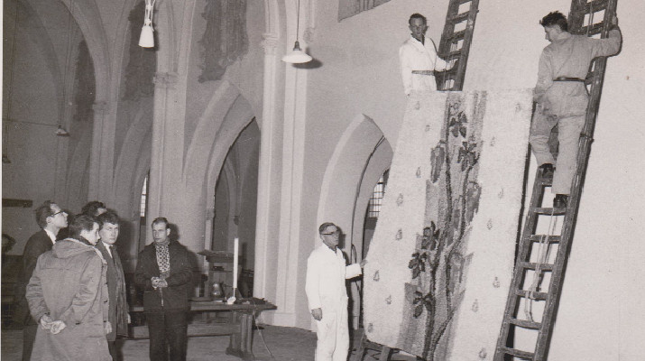 mannen hangen wandkleed op in de kerk onder toeziend oog