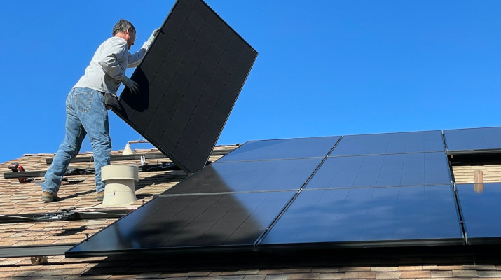 man legt zonnepaneel op dak
