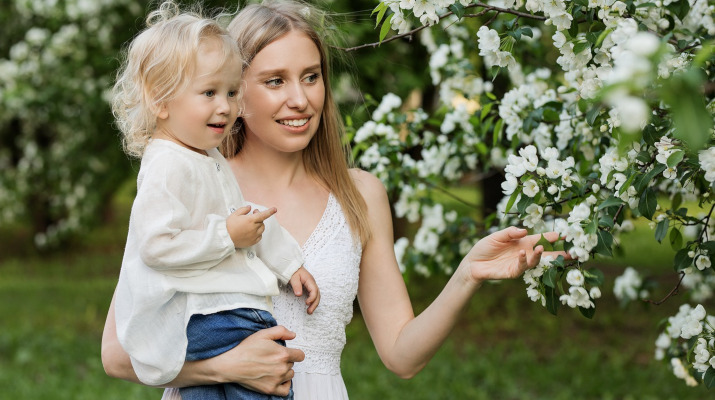 vrouw met meisje op arm bij bloeiende boom